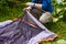 Camp in the tent - tourist setting a tent on the camping. Close up man`s hands hold a tent while setting up a tent in the forest