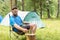 Camp in tent - young bearded man on camping in forest. Travel, lifestyle concept