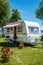 A camper trailer parked in a grassy area next to a lake Digital image