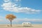 A camper van parked next to a tree on a beach