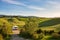 Camper van in unique green landscape, vanlife in Tuscany, Italy. Scenic dramatic sky and sunset light over cultivated hill range