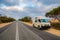 Campervan in Australia standing at the site of straight, endless road in late afternoon