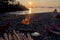 Campfire on beach at sunset with campers relaxing nearby