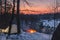 Campfire burns in the snow in the forest hill, on a background of snow covered trees and mountains campfire burning in cold winter