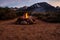 Campfire flames in rock fire pit in desert at base of mountains