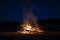 Campfire at night, with its soothing flickering flames and red and orange glow of the burning logs at dark night