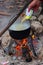 Campfire outdoors at inhabited place. Cooking meal with open fire and old coocking equipment. Cooking process when