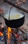 Campfire outdoors at inhabited place. Cooking meal with open fire and old coocking equipment. Cooking process when