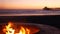 Campfire pit in California USA. Camp fire on twilight ocean beach, bonfire flame by sea water waves.