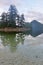 Campfire smoke partially hides tree tops of islands on calm summer evening in tranquil west coast