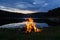 Campfire after sunset in the mountains next to a lake