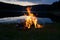 Campfire after sunset in the mountains next to a lake