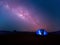 Camping. Blue tent glows under a night sky with milky way