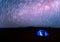 Camping. Blue tent glows under a night sky with milky way