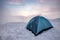 Camping blue tent at snowy hill in foggy