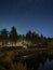 Camping with campervan at the lakeside with trees under the starry sky at night in Lapland, Sweden