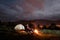 Camping evening couple sitting on boards near campfire