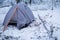 Camping in gray tent in winter forest