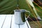 Camping metal mug on table with green tent in bcakground