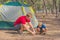 Camping people outdoor lifestyle tourists putting up setting up their green grey campsite in summer forest near lazur