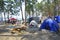 Camping in a pines forest on a riverside, tents and people relaxing