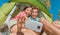 Camping selfie fun couple tourists holding phone taking self portrait photos in tent during summer vacation travel