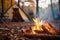 Camping site with fire lit in fire pit in Autumn woods with beautiful Fall foliage colors.
