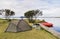 Camping site with a tent, two folding chairs and boats at the coast of Myvatn lake, Iceland