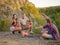 Camping students near bonfire on a natural background. Cute couples eating marshmallows. Picnic day concept. Copy space.