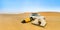 Camping in the Sudanese desert with two small tents, an off-road vehicle and a sand dune in the background