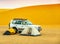 Camping in the Sudanese desert with two small tents, an off-road vehicle and a sand dune in the background