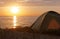 Camping at sunset on the sea, tourist tent on the beach