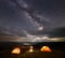 Camping tent on mountain at night under very starry sky against of luminous town