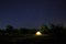 Camping tent under beautiful night sky full of stars. Starry night sky above illuminated touristic tent