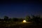 Camping tent under beautiful night sky full of stars. Starry night sky above illuminated touristic tent