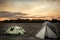 Camping tents on camping sites on summer flatland field plain and dramatic sunset sky during camping holidays