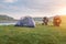 Camping tents and traveling motorcycle on flower meadows beside river