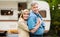 Camping together. Mature couple hugging each other on family vacation near their trailer