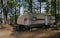 Camping trailer in the shade near a lake