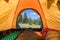 Camping with traveler stretching legs in sleeping bag on orange tent at national park