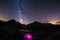 Camping under starry sky and milky way at high altitude on the Alps. Illuminated tent in the foreground and majestic mountain peak