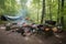 campsite setup with cooking gear and campfire surrounded by woods