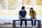 On a campus, a couple of students are studying together, and a teenager sits on a seat beside a sports court with a book