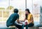 On a campus, a couple of students are studying together, and a teenager sits on a seat beside a sports court with a book