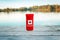 Can of beer in red cozy beer can cooler with Canadian flag standing on wooden pier by lake outdoor. Celebrating Canada Day
