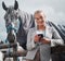 Can you make it look like he loves me. an attractive woman using her cellphone while posing with a horse in an enclosed