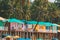 Canacona, Goa, India. Famous Painted Guest Houses On Beach Against Background Of Tall Palm Trees In Sunny Day
