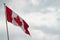 Canada flag with blue sky and clouds