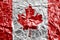 Canada flag depicted in paint colors on shiny crumpled aluminium foil closeup. Textured banner on rough background