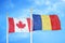 Canada and Romania two flags on flagpoles and blue cloudy sky